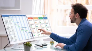 A man staring a data across dual monitors on his desk